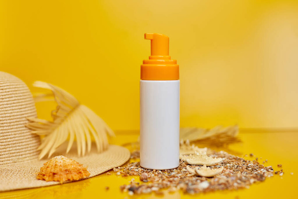Αντιηλιακό σωλήνα mockup με κοχύλια, άμμο κίτρινο φόντο, καλοκαιρινές διακοπές και spf uv-protecting έννοια φροντίδας του δέρματος. - Φωτογραφία, εικόνα