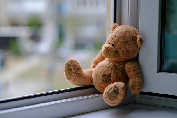 Bear childrens soft toy sitting edge an open window.Concept accidents with children - Fotó, kép
