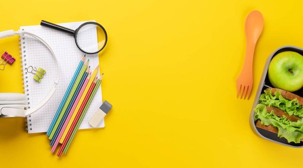 School supplies, stationery, and lunch box on yellow background. Education and nutrition. Flat lay with blank space - Φωτογραφία, εικόνα
