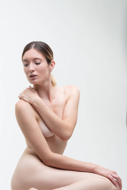 концепція краси - наполовину бюстгальтер гола жінка прикриває груди рукою і рукою, з так званим ручним бюстгальтером. Дивлячись вниз
. - Фото, зображення
