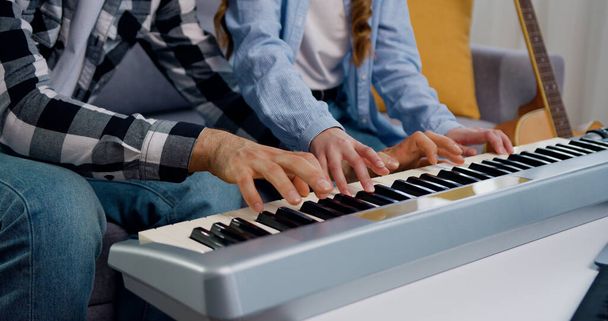 Close-up of hands of father and daughter playing electric piano together at home. Weekend activity happy family lifestyle concept. Hobby, music and youth concept. - Foto, Imagem