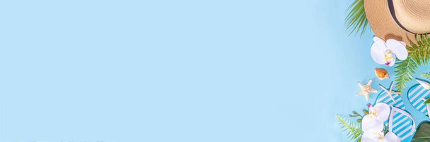 Hellblau gefärbte Sommerurlaub, Reisen und Sommerurlaub Hintergrund. Helles Flatlay mit tropischen Blättern und Blüten, Muscheln, Seesternen, Flip-Flops, Hut, Strandaccessoires, Kopierraum von oben - Foto, Bild