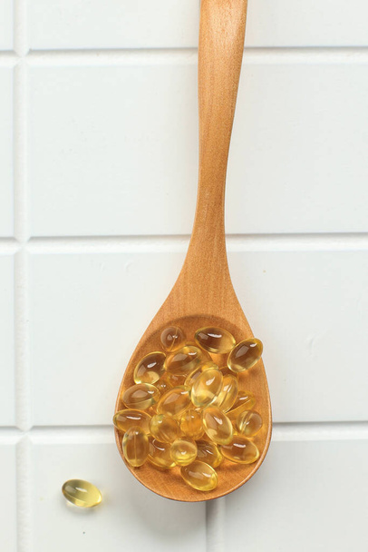 Cod Liver Oil Omega Three 3 Gel Capsules on Wooden Spoon,  Isolated on White Table - Photo, Image