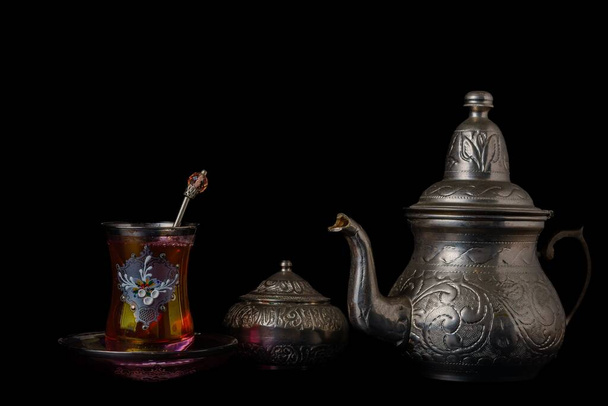 tea cup decorated with teapot and metal sugar bowl isolated on black background - Photo, Image