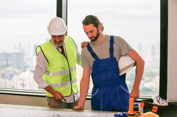 Mannelijke ingenieurs op de bouwplaats, met blauwdrukken. - Foto, afbeelding