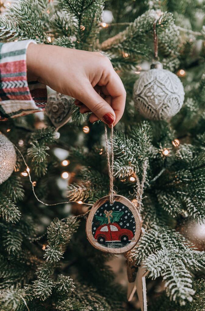 Close-up photo of woman decorating christmas tree with diy handpainted ornament - Zdjęcie, obraz
