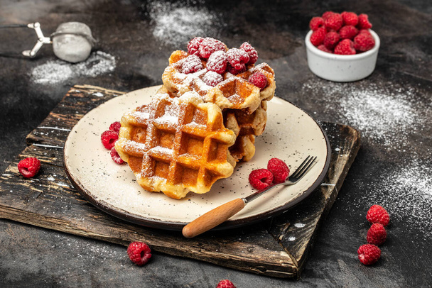 Belgian waffles with raspberries with sugar powder. Traditional belgian waffles with fresh fruit. banner, menu, recipe place for text, top view. Delicious breakfast or snack. - Foto, immagini