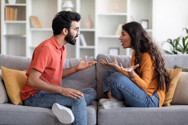 Relationship Problems. Portrait Of Young Indian Couple Arguing At Home, Eastern Millennial Spouses Sitting On Couch And Screaming At Each Other, Suffering Misunderstanding And Marriage Crisis - Фото, зображення