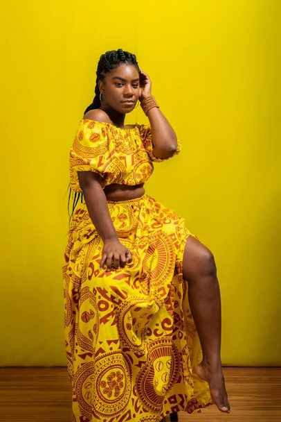 Young woman wearing colorful long clothes over yellow background. Natural expression. - Photo, image