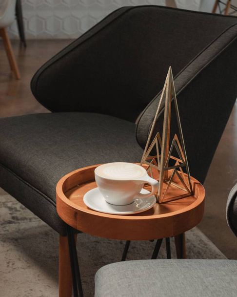 Függőleges egy szék és dohányzóasztal cappuccino és háromszög dekoráció - Fotó, kép