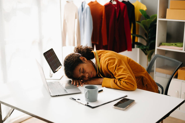 tired  brunette, dark skinned woman on desk in modern office of fashion designer with  laptop and tablet pc - Φωτογραφία, εικόνα