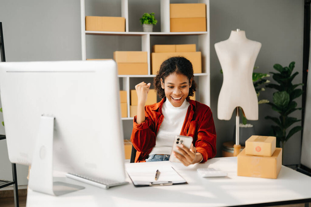 Young business owner African woman prepare parcel boxes and  check online orders for deliver to customer on computer, Shopping Online concept. - Φωτογραφία, εικόνα