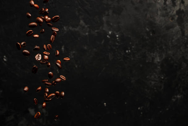 Roasted coffee beans falling on black background, Concept for coffee product advertising, Selective focus, place for text. - Foto, Bild