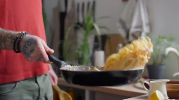 Gehakt schot van onherkenbare man gooien hete spaghetti in koekenpan tijdens het koken pasta in de keuken - Video