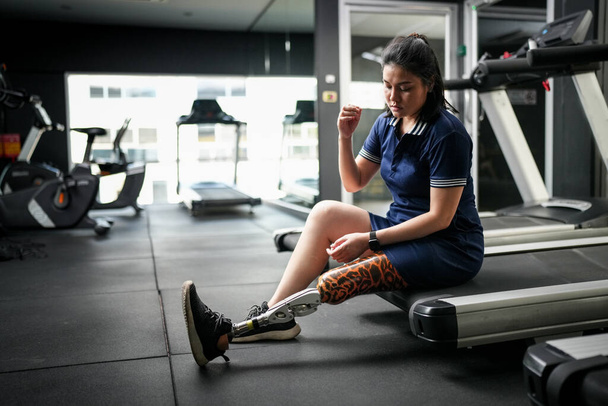 Egy mozgássérült atléta nő portréja, akinek műlába van fitnessz órán. Közelkép a bionikus protézislábon. - Fotó, kép