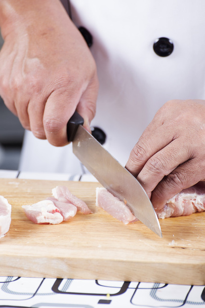 Chef cutting raw pork on wooden board - Foto, afbeelding