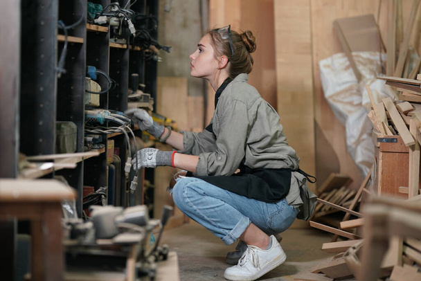 Pequeño negocio de una mujer joven. Hermosa joven trabajadora en un taller de muebles, midiendo madera. - Foto, imagen
