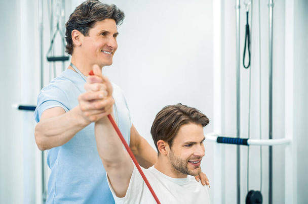 Physical therapy. Young man having a physical therapy session with a doctor - Foto, imagen