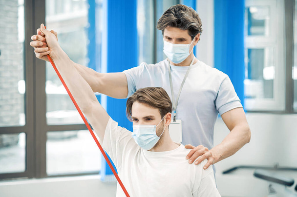 Rehabilitation. Doctor and patient in protective masks having a workout in a rehabilitation center - Φωτογραφία, εικόνα