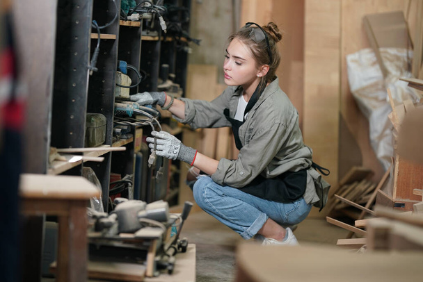 Nuori kaunis nainen tekee työtä puuseppä DIY työpaja huone. Pienyrityksen omistaja, nuori nainen, joka työskentelee huonekalutehtaalla. - Valokuva, kuva