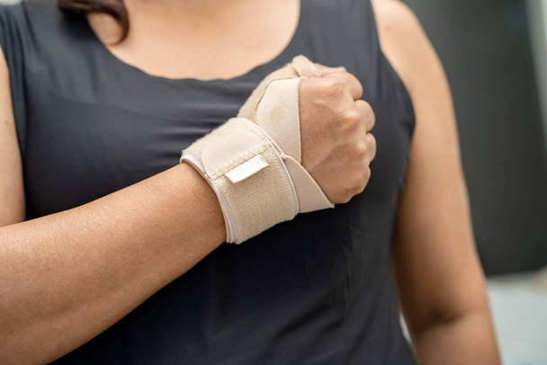 アジアの女性はオフィスで手と指でデ · ケルヴァン症候群を治療するために弾性包帯を使用. - 写真・画像