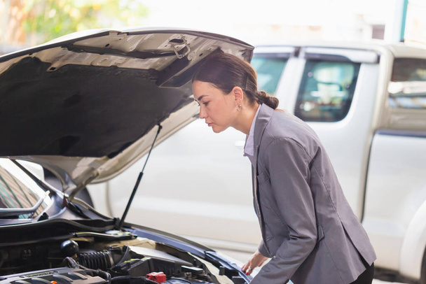 Female manager in a car service. Woman at a car garage getting mechanical service, Car repair, and maintenance concepts - Photo, Image