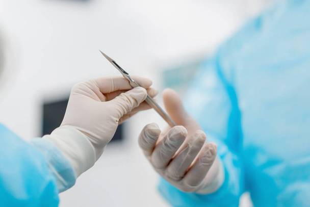 zdravotní sestra ve sterilní rukavici ruce skalp chirurgické nástroje k chirurgovi během operace v nemocnici - Fotografie, Obrázek