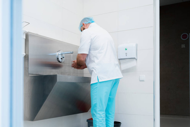 Zabieg dezynfekcji w klinice chirurg myje ręce w zlewie przed operacją - Zdjęcie, obraz