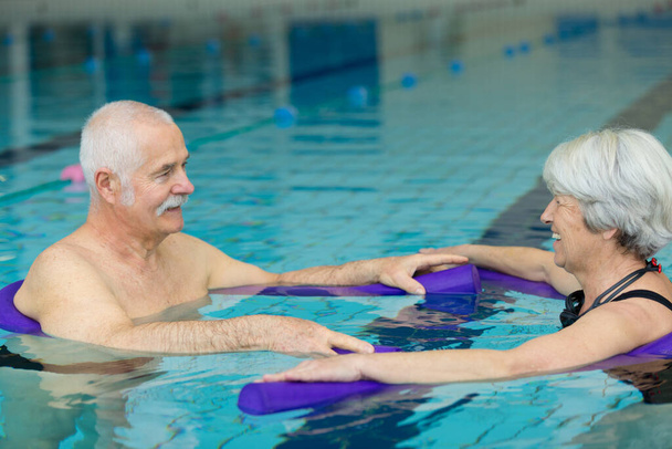 elderly couple doing exercise movement in swimming pool - 写真・画像