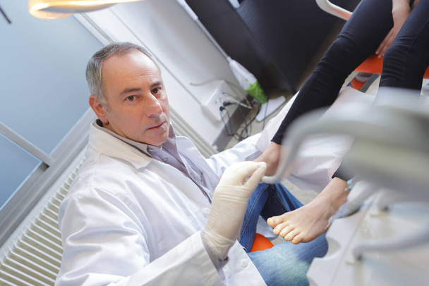 woman receives foot examination from gloved podiatrist - Photo, Image