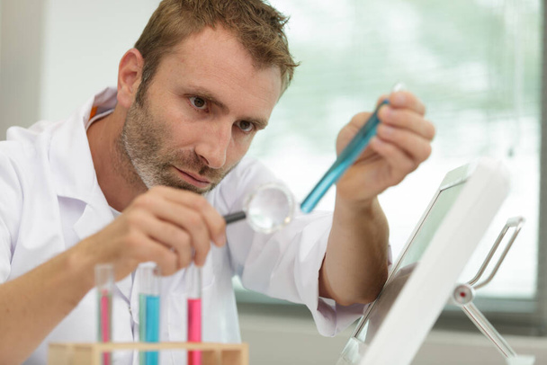 scientist looking at test tube through a magnifying glass - Φωτογραφία, εικόνα