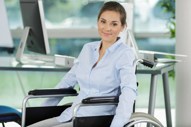 woman in wheelchair at workplace - Foto, Bild