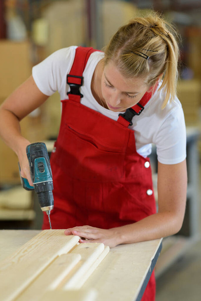 female carpenter drilling wood in workshop - Valokuva, kuva