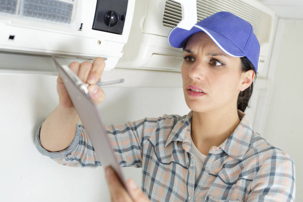 happy female worker is repairing air conditioner - Zdjęcie, obraz