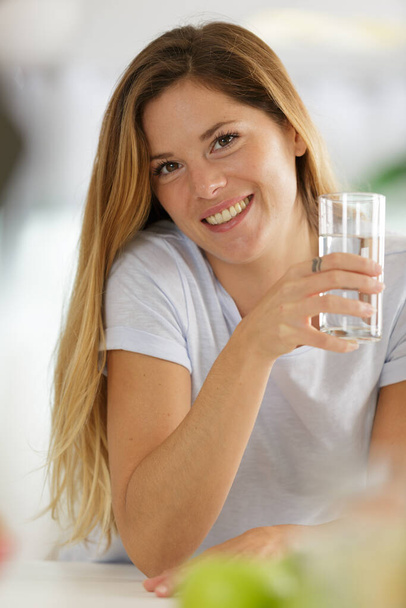 beautiful young woman smiling while holding a glass of water - Foto, immagini