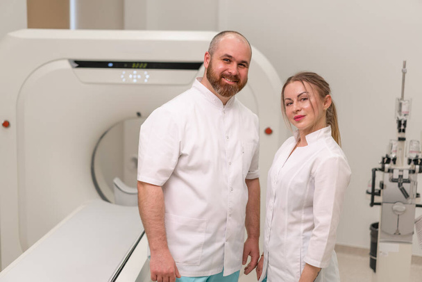 smiling and satisfied doctors in uniform posing near magnetic resonance imaging machine concept professions and medicine - Photo, Image