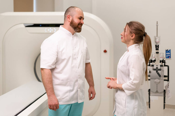 usmívající se a spokojení lékaři uniforma diskutovat o práci v blízkosti magnetické rezonance zobrazovací stroj medicíny koncept - Fotografie, Obrázek