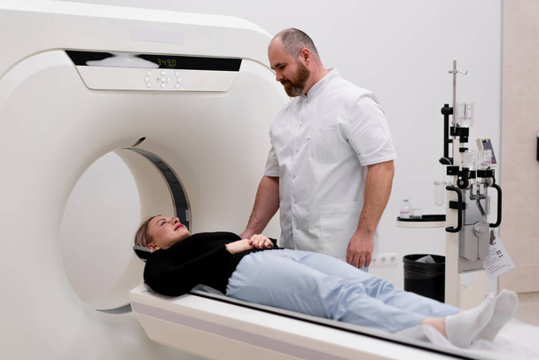 Een radioloog voert een computer tomografie procedure in een medische kliniek Een hoofd onderzoek wordt uitgevoerd op de patiënt - Foto, afbeelding