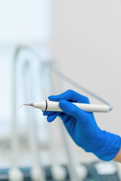 Klinikte prosedür kapanmadan önce eldivenli ellerde tartar çıkarmak için çalışan profesyonel dişçi. - Fotoğraf, Görsel