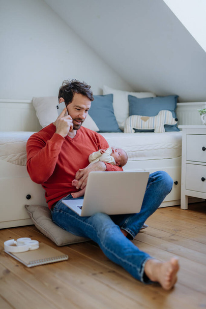 Father holding his newborn crying baby during working on a laptop. - Foto, immagini