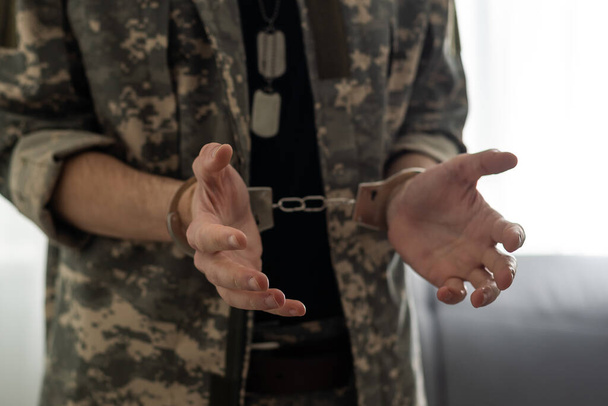 Handcuffed soldier in military army clothes. Close up of hands in handcuffs. - Photo, Image