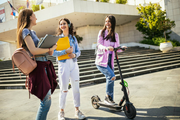 Studente op scooter studeren en praten met haar klasgenoten - Foto, afbeelding
