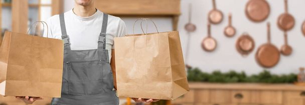 İçinde yiyecek olan kağıt torbaları taşıyan kurye, mesaj için yer. Teslimat servisi. - Fotoğraf, Görsel