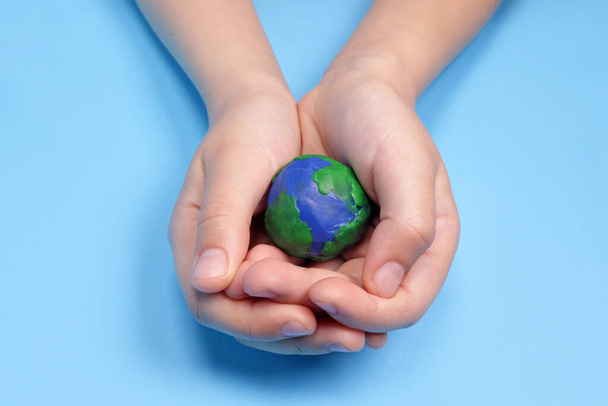 Χέρι παιδιού που κρατά πλαστικίνη πλανήτη γη, έννοια της οικολογίας - Φωτογραφία, εικόνα