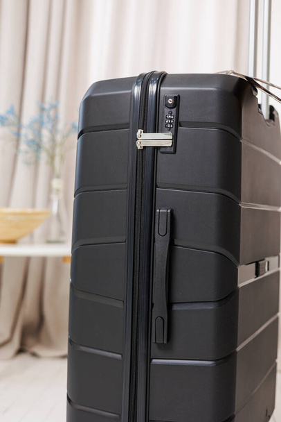 Fekete műanyag erős bőrönd poggyász szállítására fehér alapon. Fényes bőrönd utazáshoz - Fotó, kép