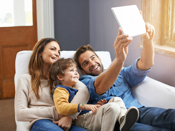 Selfie, tablet and happy family relax in a home together doing social media content on the internet or online. App, website and parents with kid or child in happiness and smile for a picture. - Photo, Image