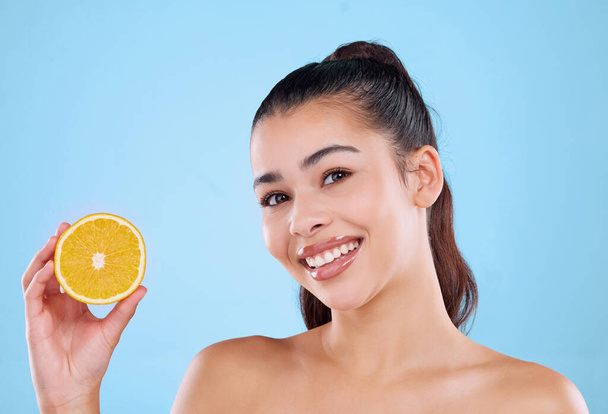Citrus je dobrý pro duši. Studio portrét atraktivní mladé ženy pózující s polovinou pomeranče na modrém pozadí - Fotografie, Obrázek