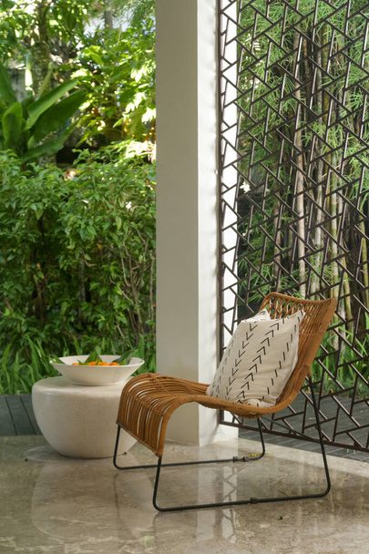 Half opened lounge area with all natural materials made furniture, rattan chairs with greenery behind - Foto, Bild
