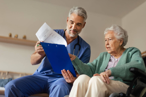 Caregiver doing regular check-up of senior client in her home. - Foto, Imagen