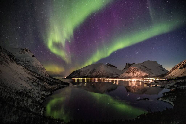 A long exposure of polar lights, a stunning display of colors, playing across the dark sky in swirls of green, purple, blue and yellow in Norway - Foto, Imagem